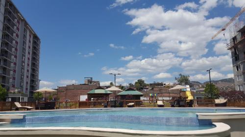 una gran piscina con mesas y sombrillas en Apartamentos EcoVivienda, en Tegucigalpa