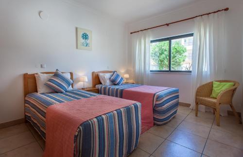 a bedroom with two beds and a chair and a window at Villa Vista Anders Mar in Lagos