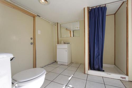 a bathroom with a toilet and a blue shower curtain at Shore Beach Houses - 119 F Franklin Avenue in Seaside Heights
