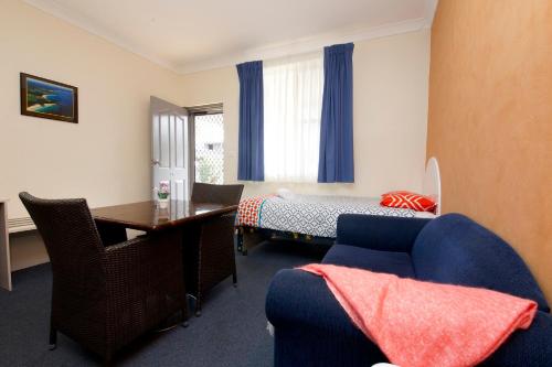 a room with a desk and a bed and a table at Tuncurry Beach Motel in Tuncurry