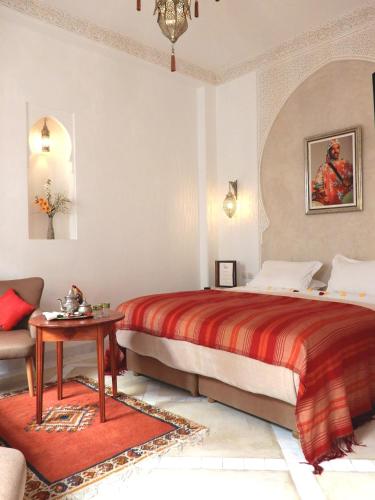 a bedroom with a bed and a table and a couch at Riad Carina in Marrakesh