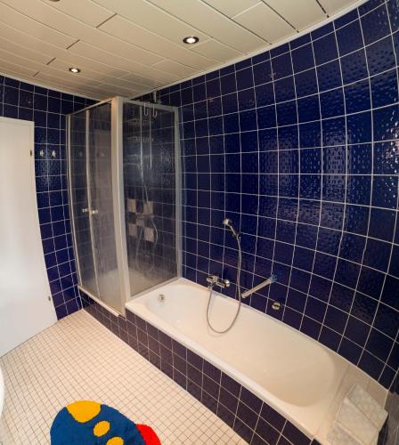 a blue tiled bathroom with a shower and a tub at Zum Ehranger Wald 2a in Trier