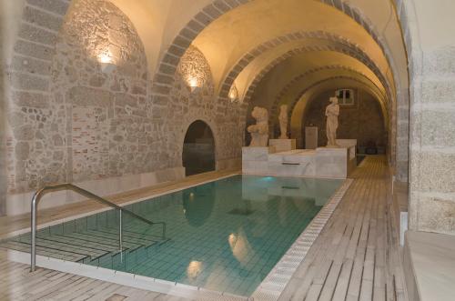 a large swimming pool in a building with a statue at Apartamentos La Plazuela Baños de Montemayor in Baños de Montemayor
