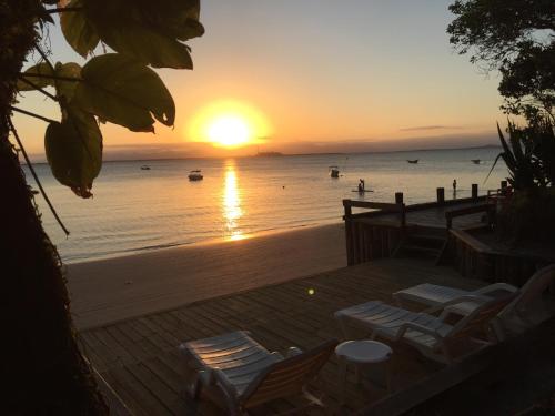 a sunset on a beach with chairs and the ocean at Pousada D'Aconchego Nova Brasilia in Ilha do Mel