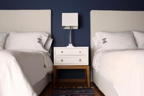 a bedroom with two beds and a night stand with a lamp at Maja Hotel Boutique in Morelia