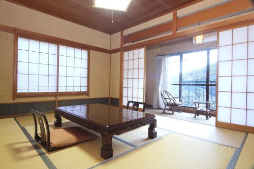 a room with a table and chairs and windows at Amagiso in Kawazu