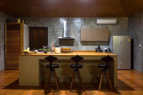 a kitchen with a counter and four bar stools at The Wes Village, incl Breakfast and Dinner in Chiang Dao
