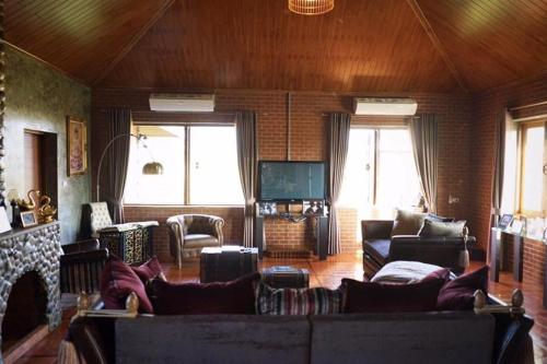a living room with a couch and a fireplace at The Wes Village, incl Breakfast and Dinner in Chiang Dao