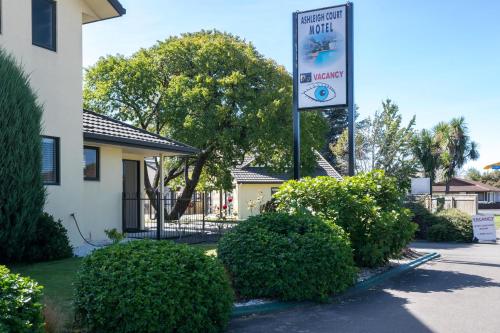 a sign in front of a house with bushes at Ashleigh Court Motel in Blenheim