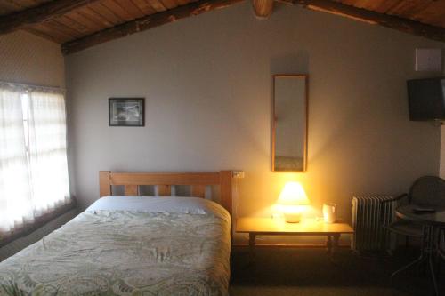 a bedroom with a bed and a lamp on a table at Barnyard Backpackers Te Anau in Te Anau