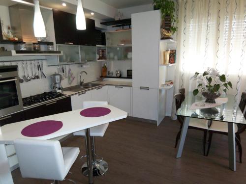 una cocina con armarios blancos, una mesa y una barra en B&B Pitstop en Anzola dell'Emilia