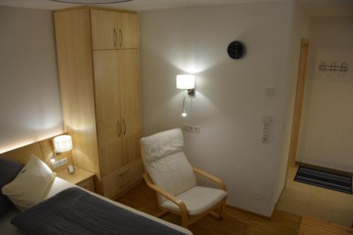 a bedroom with a bed and a chair and a cabinet at Villa Müsli in Dettingen an der Iller