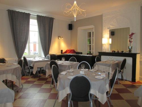 een restaurant met witte tafels en stoelen en een kroonluchter bij Logis Hostellerie Du Cheval Blanc in Sainte-Maure-de-Touraine