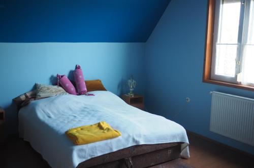 a blue bedroom with a large bed with yellow pillows at Privatzimmer Csikos in Hortobágy