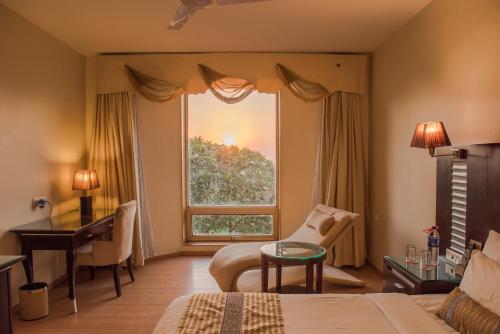 a bedroom with a bed and a desk and a window at The Red Maple Mashal in Indore