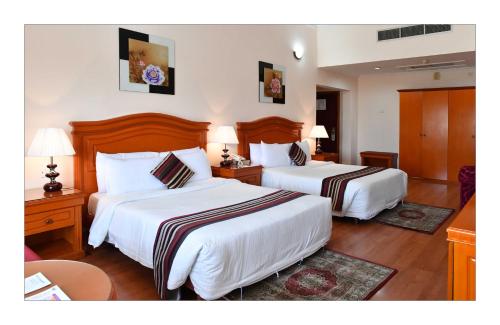 a hotel room with two beds and two tables at Gulf Gate Hotel in Manama