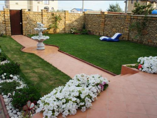 a backyard with a garden with white flowers and a playground at Bonita in Zatoka