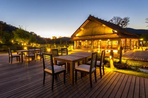 a wooden deck with tables and chairs in front of a building at Namkat Yorla Pa Resort in Ban Kat