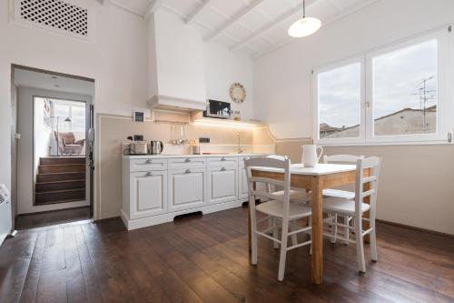 a kitchen with white cabinets and a table and chairs at Charming Attic Niche in Florence