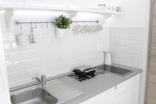 a white kitchen with a sink and a counter at Hortenzia Apartments in Hvar