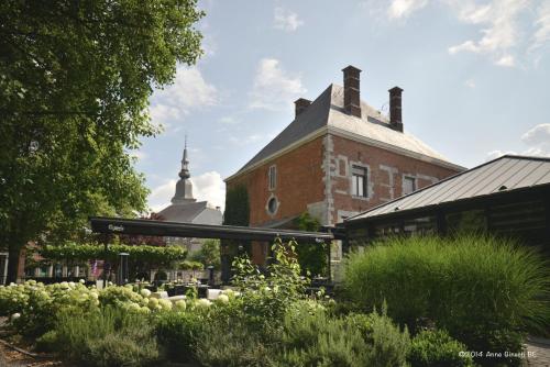 - un bâtiment en briques avec un jardin en face dans l'établissement Hôtel Le Manoir, à Marche-en-Famenne