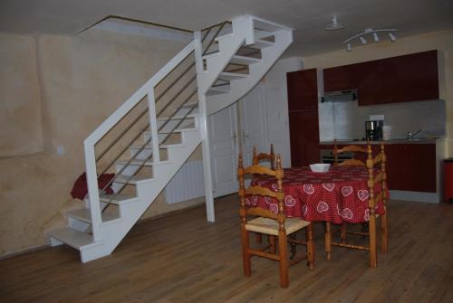 a dining room with a table and a white staircase at Gite La Chouette in Bégard