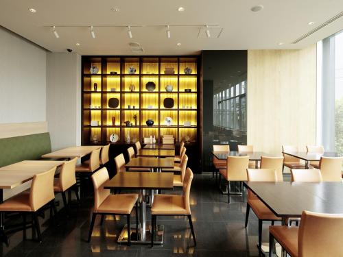 a restaurant with tables and chairs and a wall of wine bottles at Candeo Hotels Chino in Chino