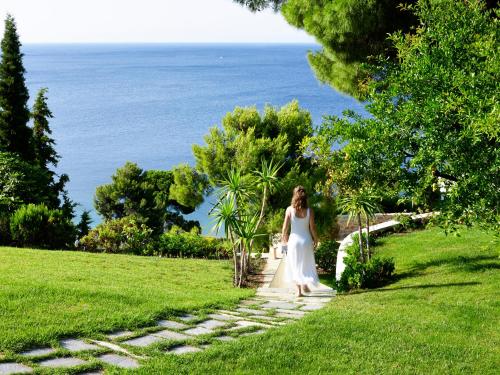 a woman in a white dress walking down a stone path at Atrium Hotel in Agia Paraskevi