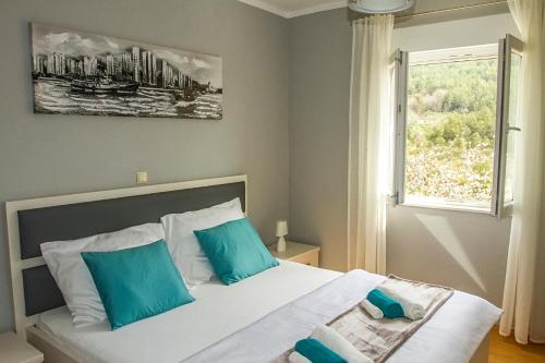 - une chambre avec un lit doté d'oreillers bleus et d'une fenêtre dans l'établissement Sea Stone Apartment, à Podstrana