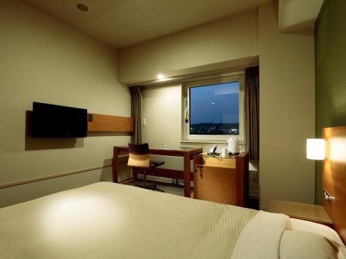 a hotel room with a bed and a desk and a window at Candeo Hotels Handa in Handa