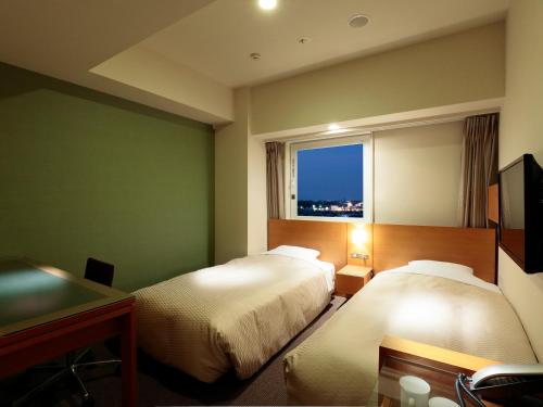 a hotel room with two beds and a window at Candeo Hotels Handa in Handa