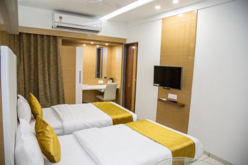 a hotel room with two beds and a television at Hotel Orange International in Surat