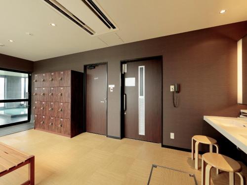 a bathroom with a sink and a counter and chairs at Candeo Hotels Ozu Kumamoto Airport in Ozu