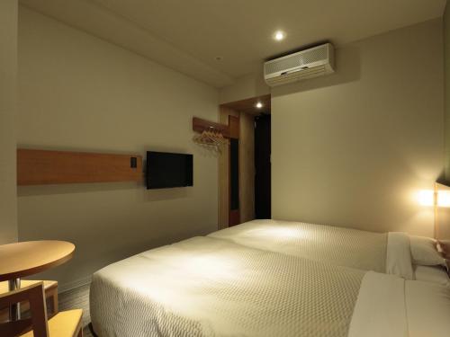 a bedroom with a white bed and a small table at Candeo Hotels Chino in Chino