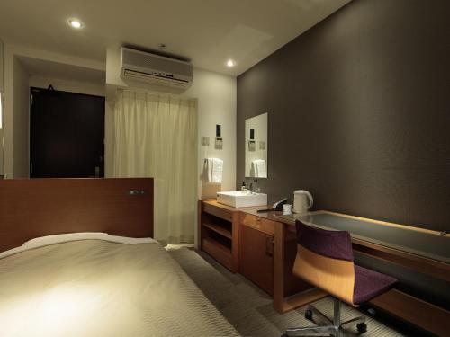 a bedroom with a bed and a sink and a desk at Candeo Hotels Chino in Chino