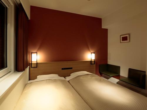 a bed in a room with lights on the wall at Candeo Hotels Ozu Kumamoto Airport in Ozu