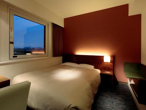 a hotel room with a bed and a window at Candeo Hotels Ozu Kumamoto Airport in Ozu