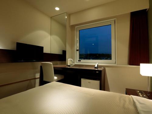 a room with a bed and a desk and a window at Candeo Hotels Ozu Kumamoto Airport in Ozu