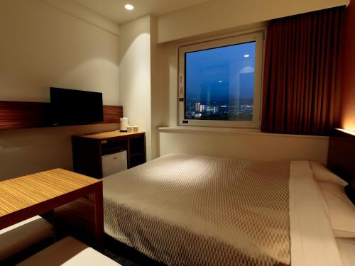 a bedroom with a bed and a window with a view at Candeo Hotels Ozu Kumamoto Airport in Ozu