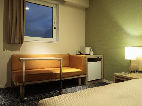 a hotel room with a couch and a window at Candeo Hotels Shizuoka Shimada in Shimada