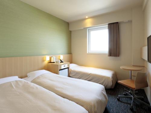 a hotel room with two beds and a window at Candeo Hotels Shizuoka Shimada in Shimada