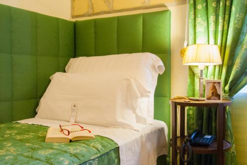 een slaapkamer met groene muren en een bed met een boek en een lamp bij Domus Mariae Benessere in Siracusa