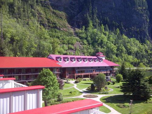 a building with a red roof and a mountain at Three Valley Lake Chateau in Revelstoke