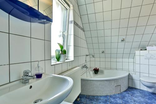 a white bathroom with a tub and a sink at Ferienhaus Kottmann in Bremerhaven