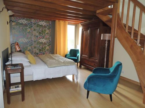 - une chambre avec un lit et deux chaises bleues dans l'établissement chambres d'hôtes le Boyer, à Mantenay-Montlin