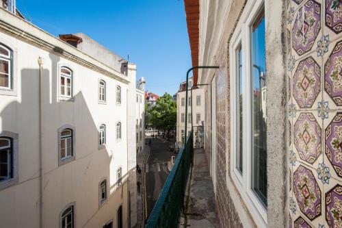 an alley between two buildings with mosaics on the walls at Duque-Chiado Downtown in Lisbon