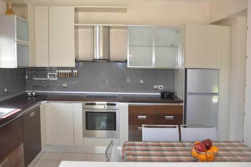 uma cozinha com armários brancos e uma taça de fruta numa mesa em Beautiful house with garden in Rhodes em Ialyssos