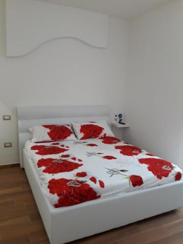 a white bed with red flowers on it at Il sogno di Ele in Polignano a Mare