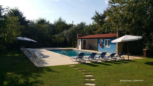 una piscina con sillas y sombrillas junto a una casa en Casa do Mercador en Real