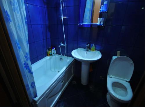 a blue tiled bathroom with a toilet and a sink at Apartment Urushadze in Batumi